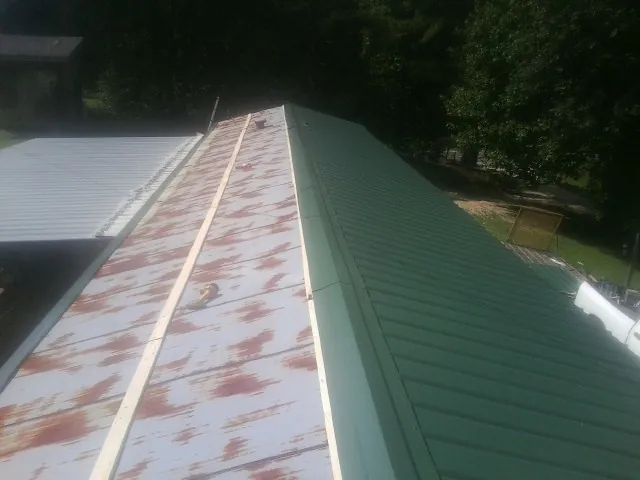 Old rusted panels beside newly installed green metal roofing — Wind Damage Roof Repair by Roofing Brothers in East Ryegate