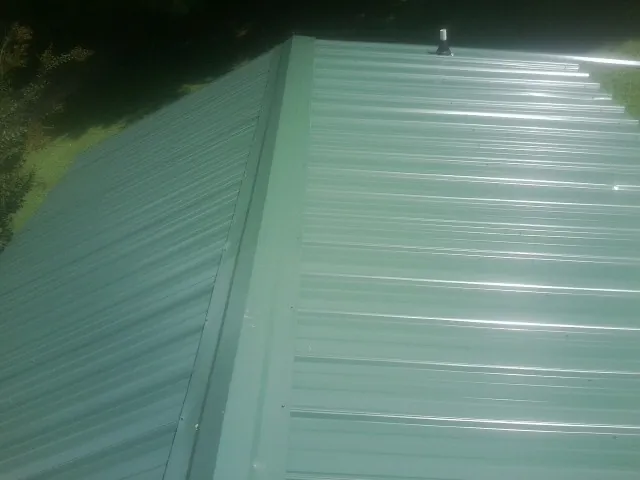 New green metal panels meeting at the ridge of a roof — Flat Roof Repair work by our crew in East Ryegate