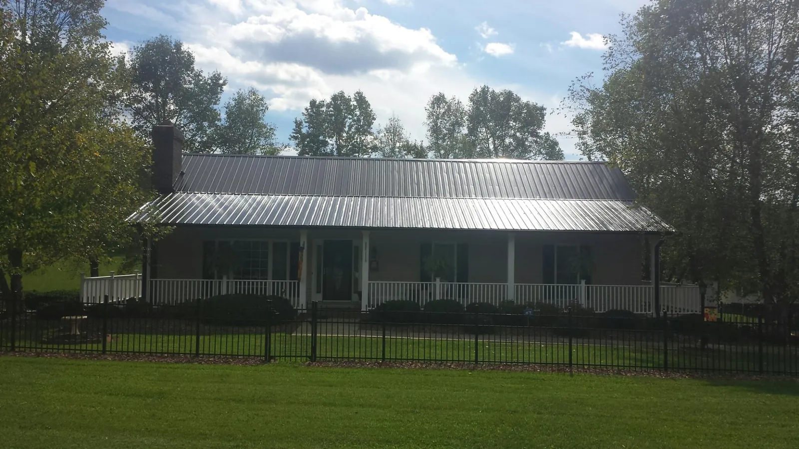 Gray metal roof on a brick ranch with a full width front porch — Gutter Guard Installation work by our crew in East Ryegate
